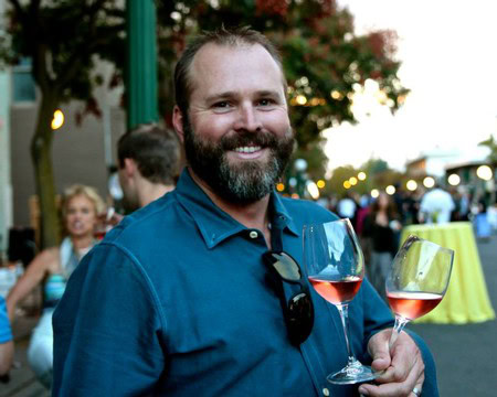 Smiling man holding two glasses of rosé wine at a wine event in Lodi, California.