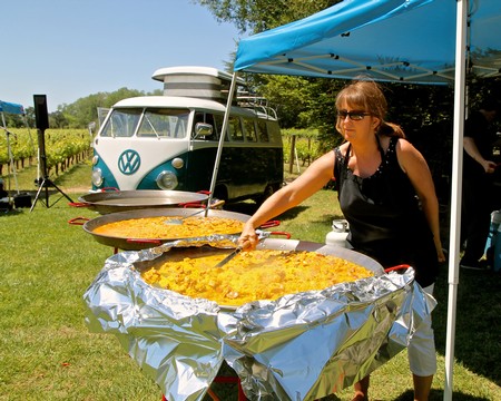Woman serving large pan of paella at Lodi Winegrape Commission outdoor event.