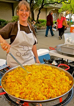 Woman cooking yellow rice dish at Lodi Winegrape Commission outdoor event.