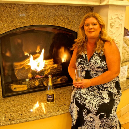 Woman holding a glass of wine near a fireplace at a Lodi Winegrape Commission event.
