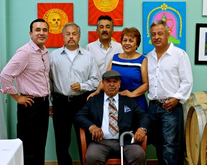 Group of six diverse individuals, including an elderly man with a cane, posing in front of colorful artwork at Lodi Winegrape.