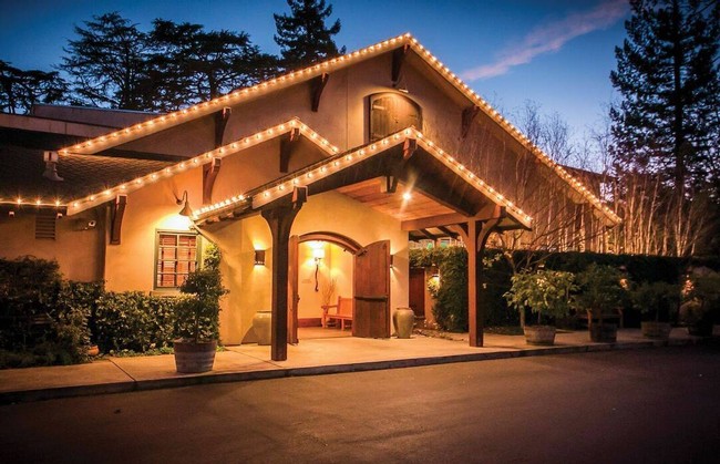 Charming winery building with string lights and wooden accents at dusk, surrounded by trees.
