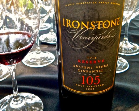 Bottle of Ironstone Vineyards Zinfandel 2014 Reserve with wine glasses on a table.