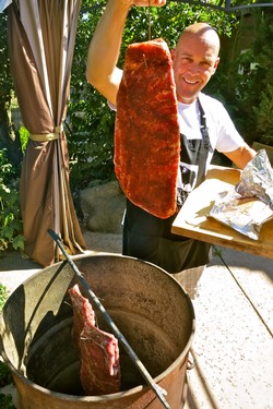 Man grilling a large piece of meat outdoors at Lodi Winegrape Commission event.