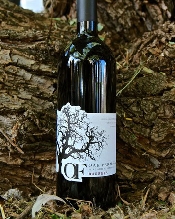 Bottle of wine from Oak Farm Vineyards in Lodi, California, with a tree illustration on the label, placed outdoors.