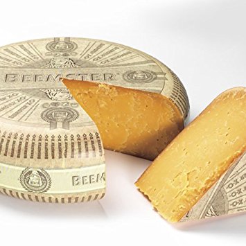 Cheese wheel wrapped in dollar bill design, with a slice cut showing the yellow interior.