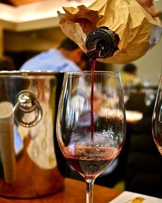Red wine being poured into a glass at a Lodi wine event, showcasing local winegrapes and wine production.