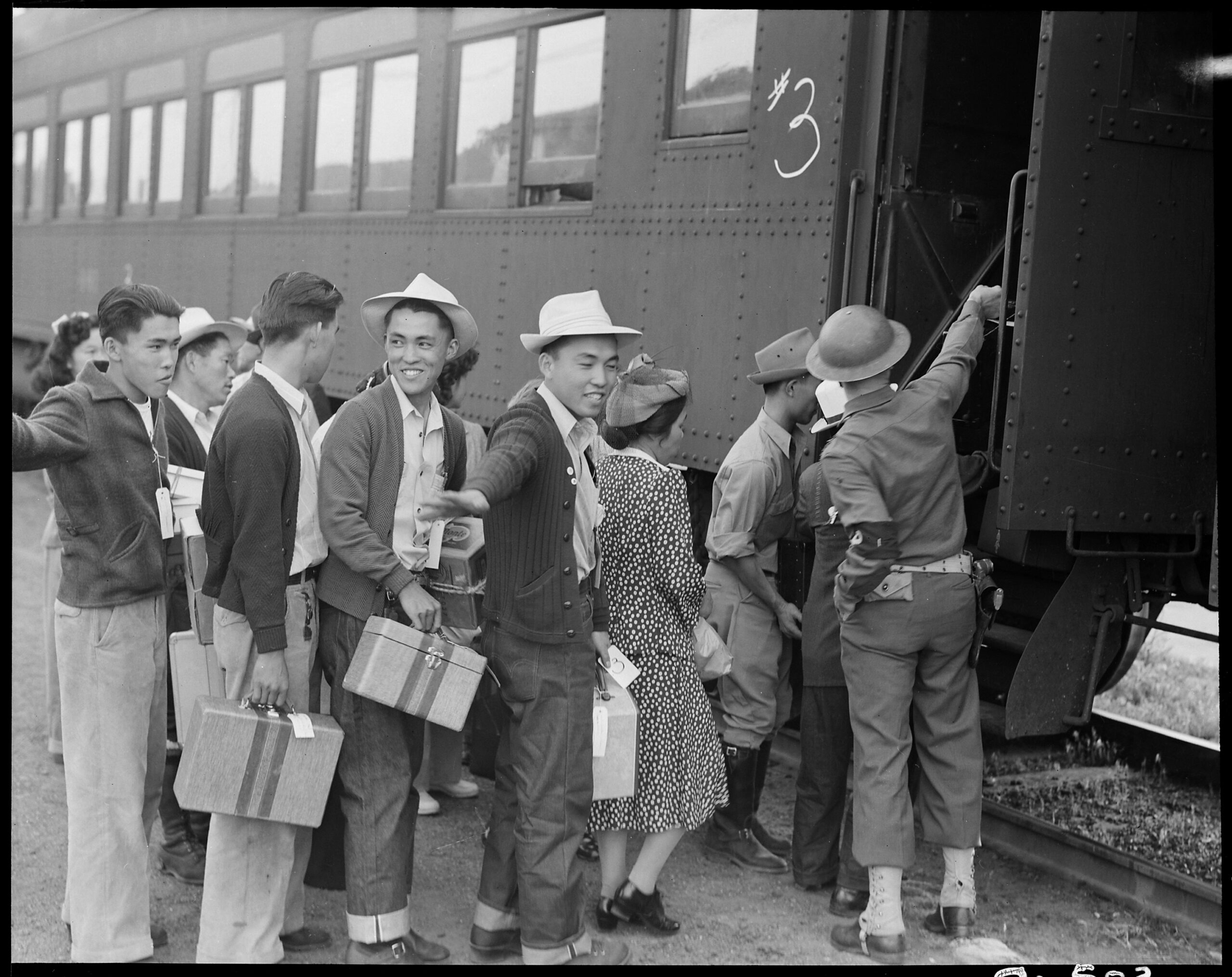 Historical black and white photo of people boarding a train, likely during the early 20th century.