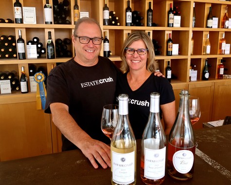 Two staff members from Lodi Winegrape Commission smiling at winery with wine bottles and glasses.