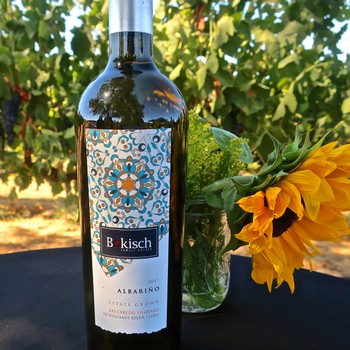 Bottle of Alsarino wine from Lodi Winegrape Commission with sunflower and vineyard background.