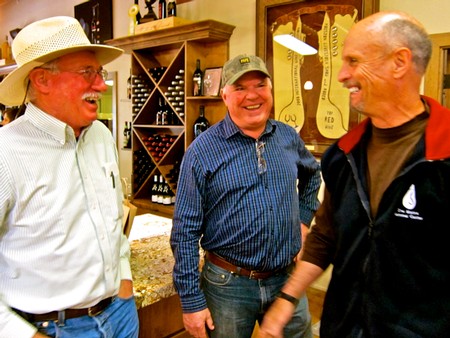 Three men smiling and talking at a wine tasting event, representing Lodi Winegrape Commission.