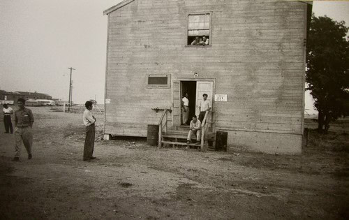 People gathered outside a wooden building, possibly related to Lodi Winegrape Commission activities.