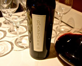 Close-up of a wine bottle labeled 'Nature' on a table with wine glasses.