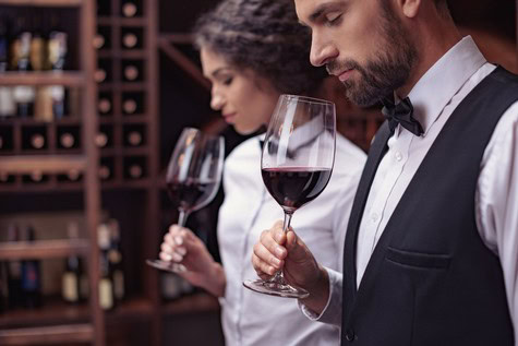 Two sommeliers tasting red wine in a wine cellar, showcasing Lodi wine quality and expertise.