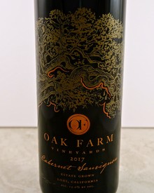 Bottle of Oak Farm Vineyard 2017 Cabernet Sauvignon with gold-embossed tree design and orange logo.