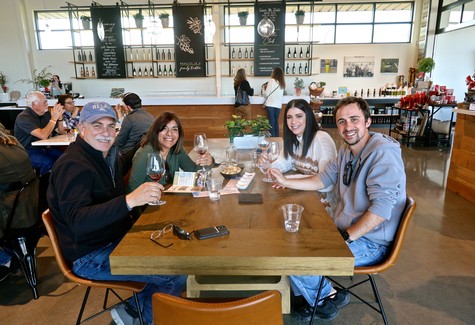 Group enjoying wine tasting at Lodi Winegrape Commission event in a modern winery setting.