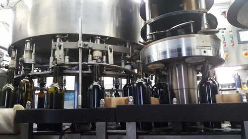 Industrial wine bottling machine filling bottles in a winery production line.