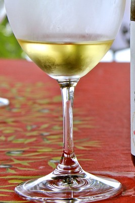 Close-up of a glass of white wine on a red table with a blurred background.