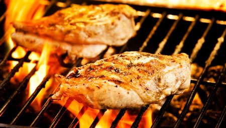 Juicy grilled chicken breasts cooking over open flame on a barbecue grill.