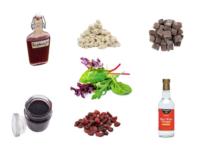 Ingredients for wine making including raspberry syrup, rice wine vinegar, dried cranberries, and fresh greens.