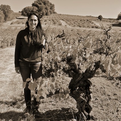 Woman standing in a vineyard with grapevines in Lodi, California, during daytime.