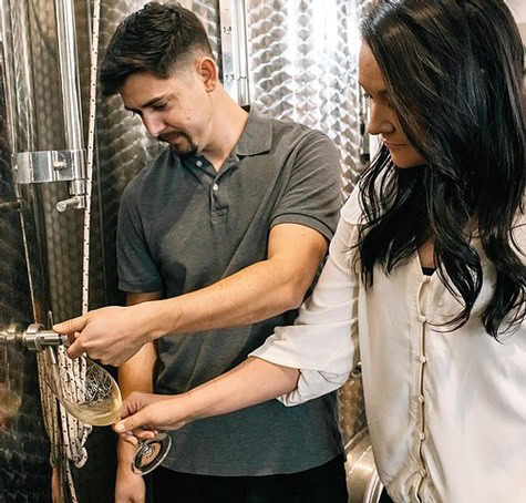Two people tasting wine in a stainless steel wine fermentation tank at Lodi Winegrape Commission.