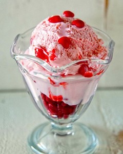Delicious cherry ice cream served in a glass dish with cherry toppings for a cool treat.