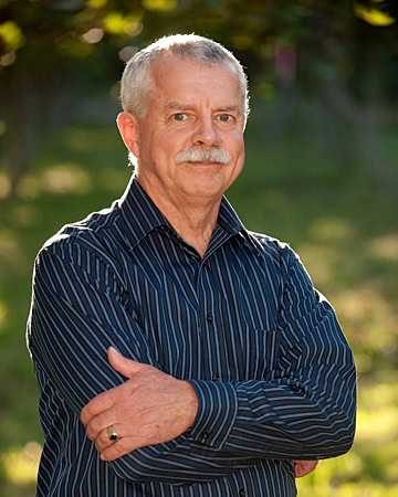Portrait of an older man with gray hair and mustache, wearing a striped shirt outdoors, representing Lodi Winegrape industry.