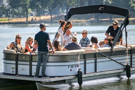 Group of people enjoying a boat tour on a lake, learning about Lodi winegrapes and local wine production.