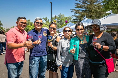 Group of diverse people enjoying wine tasting at Lodi Winegrape Commission event.