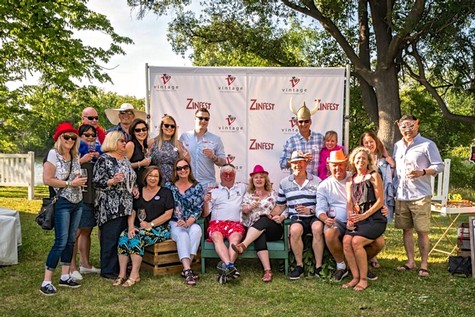 Group of people at Lodi Winegrape Commission event outdoors with trees and a banner in the background.