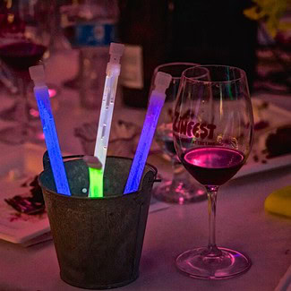 Glass of red wine and glow sticks on a table at a Lodi Winegrape Commission event.