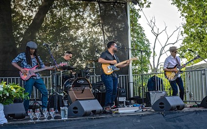Band performing live on outdoor stage at Lodi Wine event with trees in background.