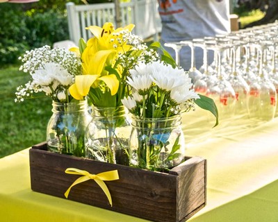 Elegant floral arrangement with yellow lilies and white daisies in glass jars for Lodi Winegrape Commission event.