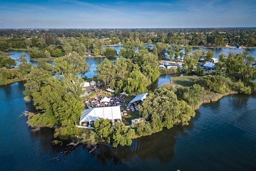 Aerial view of a scenic event on a lush island in Lodi, California, surrounded by water and vineyards.