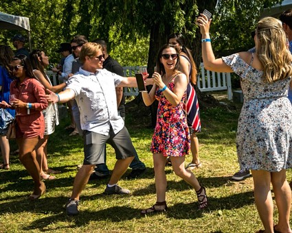 People enjoying outdoor event, dancing and taking photos at Lodi Winegrape Commission gathering.