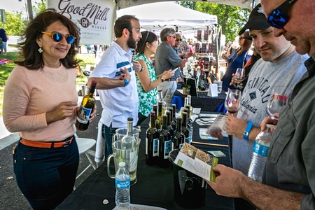 People enjoying wine tasting at the Lodi Winegrape Commission event with wine bottles and glasses on display.