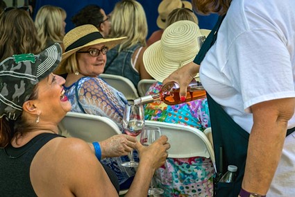 Attendees enjoying wine tasting at a Lodi Winegrape Commission event, with women wearing hats and engaging in conversation.