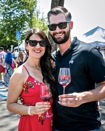 Smiling couple enjoying wine tasting at Lodi Winegrape Festival outdoors.