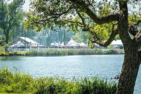 Scenic view of a lake with trees and tents set up for a wine event by the Lodi Winegrape Commission.