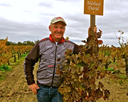 Lodi Winegrape grower Michael David in vineyard with sign, smiling, autumn season, grapevines, agricultural landscape, sunny.