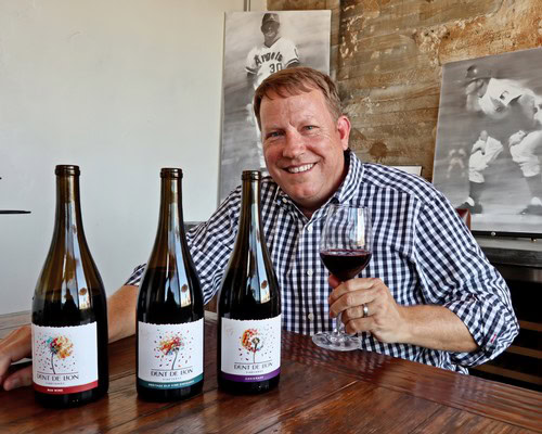 Man enjoying wine tasting at Lodi Winegrape Commission with three wine bottles on table.