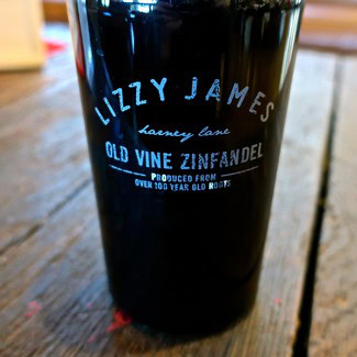 Close-up of a black wine bottle with blue and white text from Lodi Winegrape Commission.