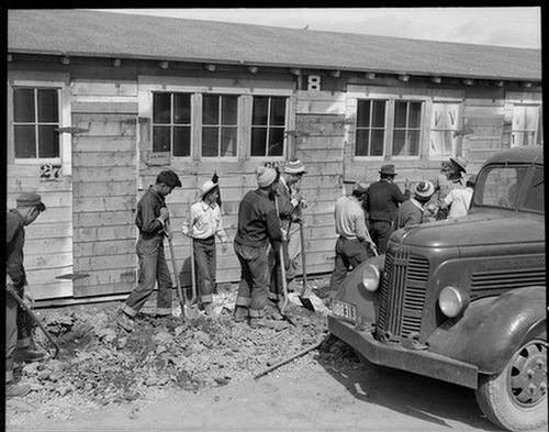 Workers in vintage clothing working in a vineyard with an old truck nearby, historical scene from Lodi Winegrape Commission.