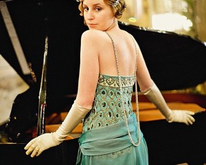 Elegant woman in vintage dress at a grand piano, representing Lodi Winegrape Commission's cultural events and wine heritage.