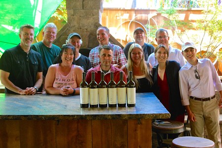 Group of people at Lodi Winegrape Commission event with wine bottles on table.