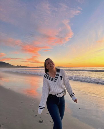 Woman enjoying sunset on the beach with colorful sky and ocean waves in Lodi Winegrape region.
