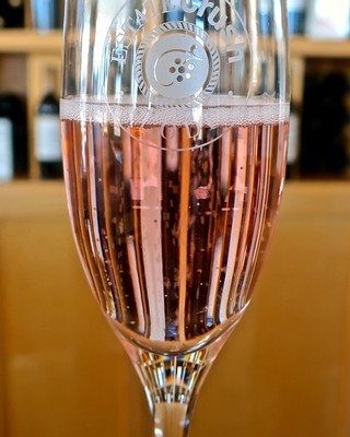Glass of sparkling rosé wine from Lodi Winegrape Commission, showcasing pink color and bubbles.