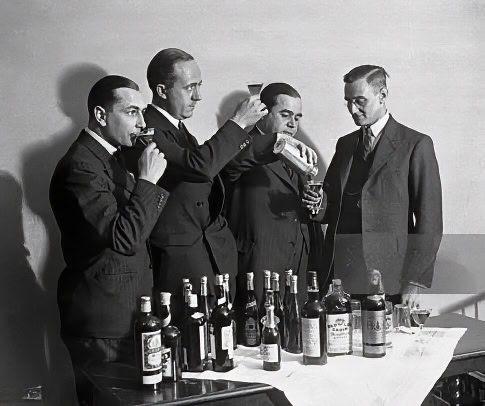 Historical black and white photo of men tasting wine at a wine event, showcasing Lodi wine industry.