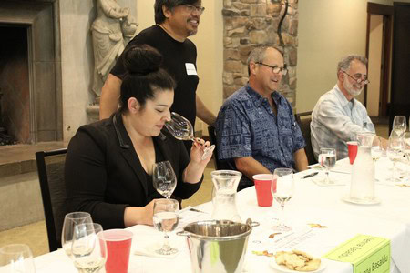Group of people tasting wine at a Lodi Winegrape Commission event, with wine glasses and a wine expert guiding the session.